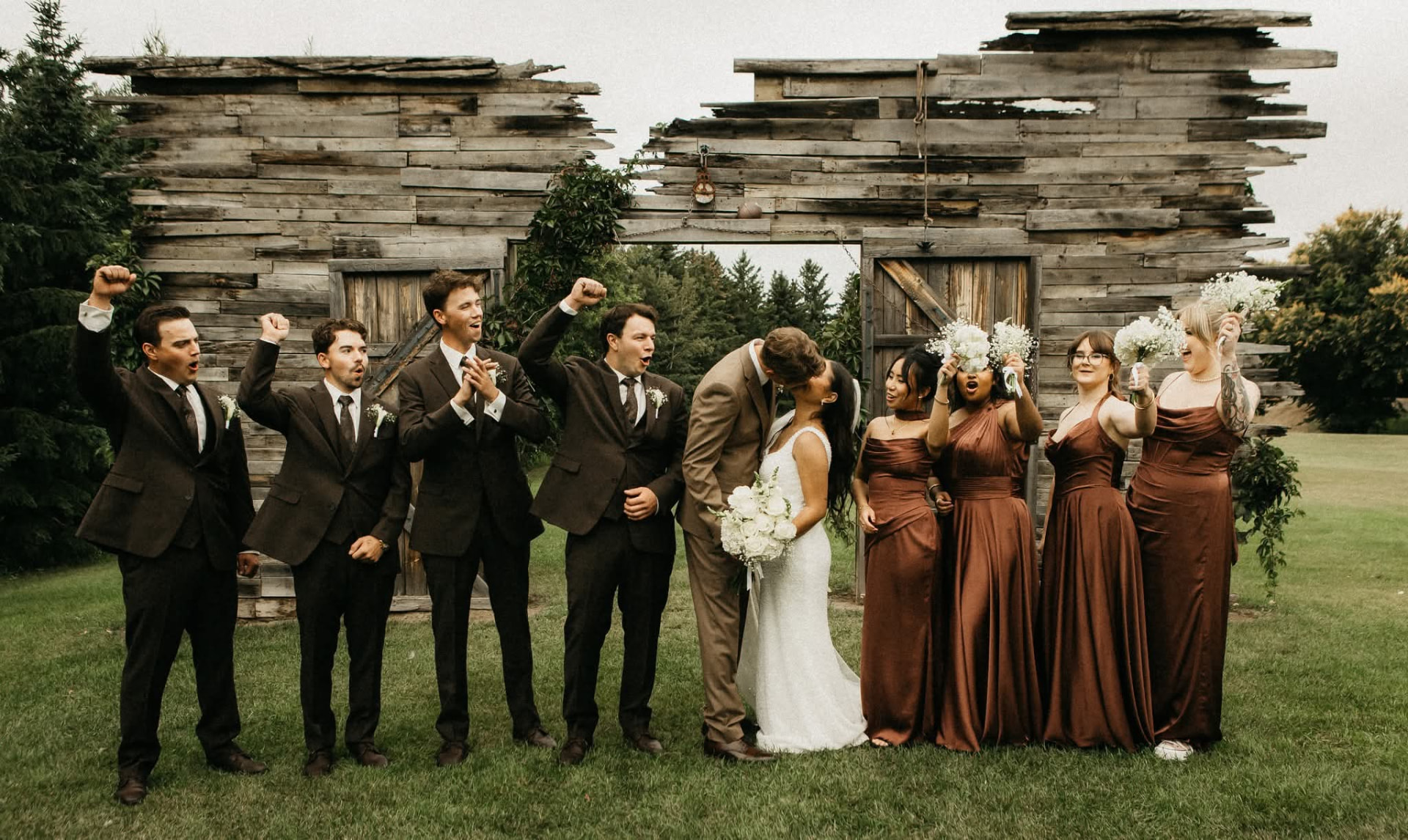 Wedding party cheering at the old barn wall