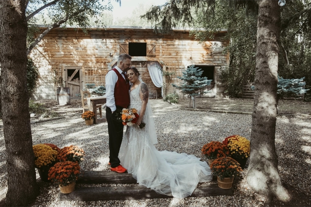 The newlyweds embracing on the wooden steps in front of the barn